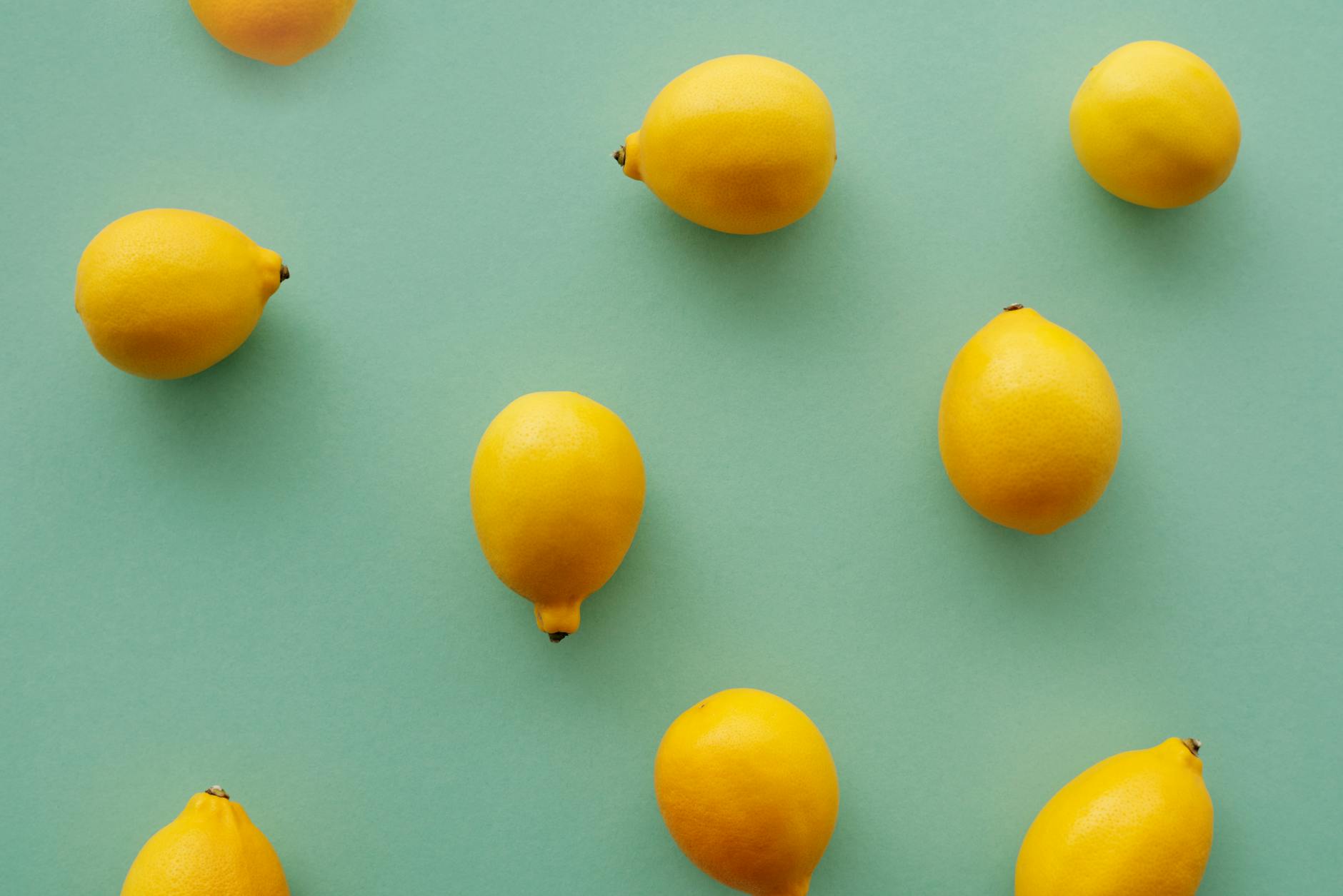 Bright yellow lemons arranged on a pastel green background, symbolizing fresh pleasure without rush