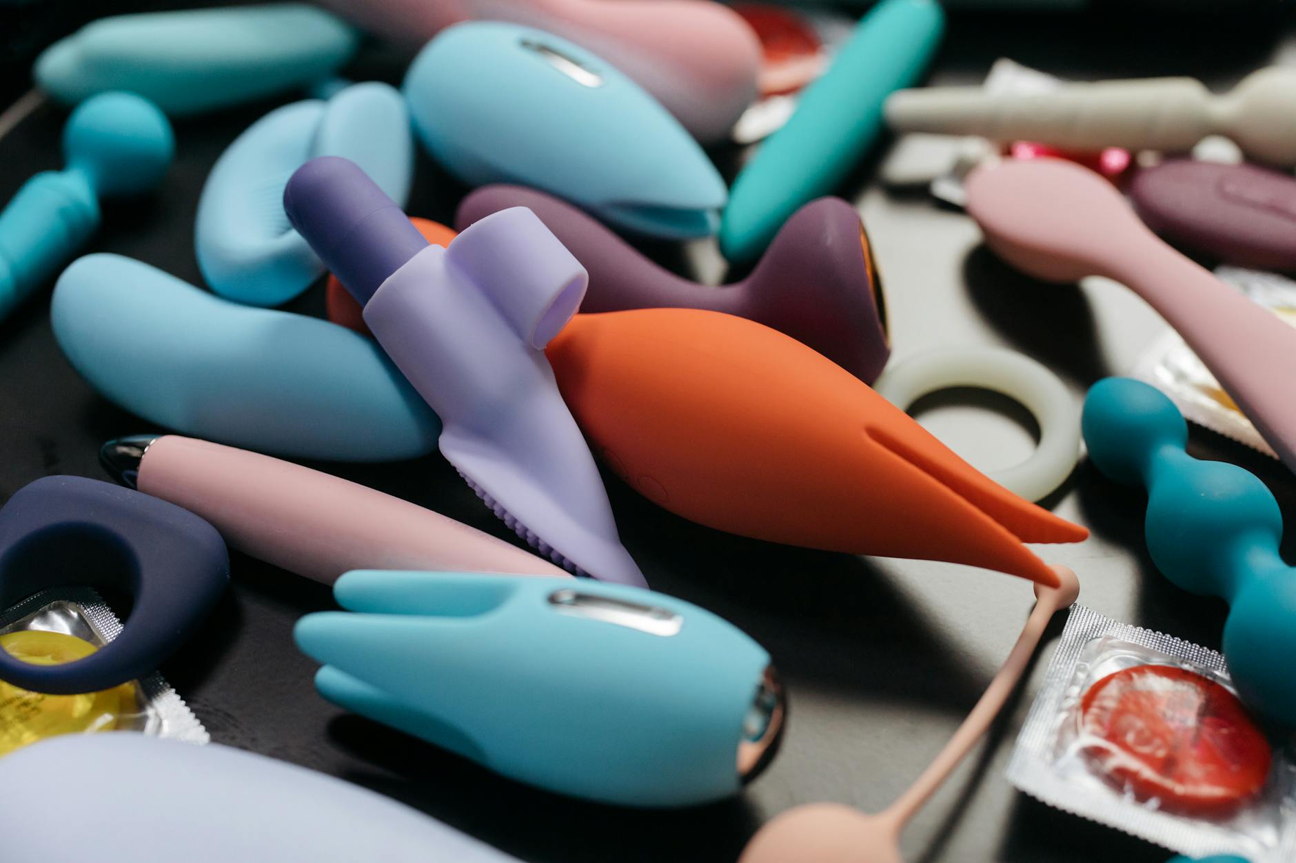 Array of colorful silicone adult toys on a surface, representing self-care and intimate reconnection