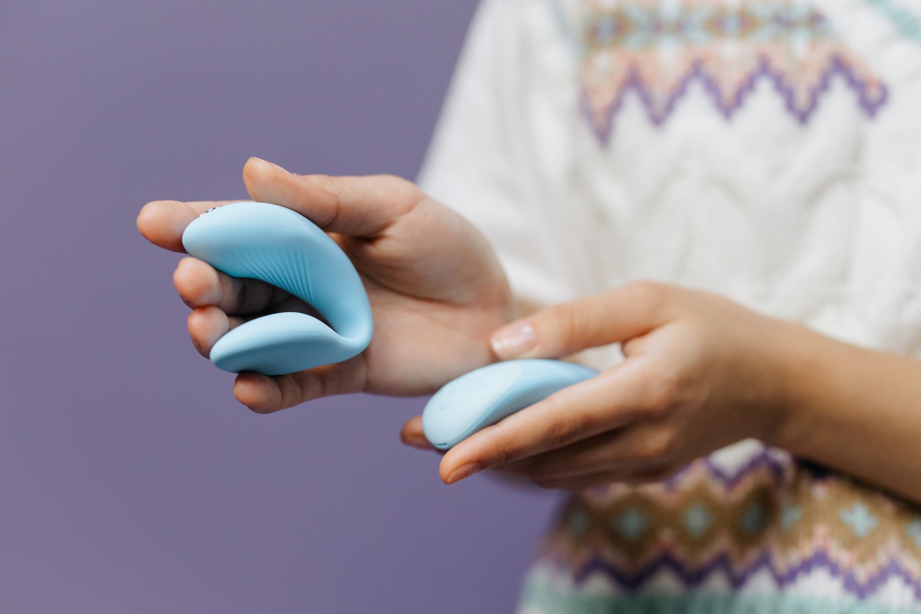 A hand gently holding a sleek blue vibrator, symbolizing careful, sensitive pleasure exploration.